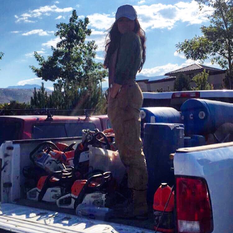 Biologist standing in the bed of a truck with chainsaws